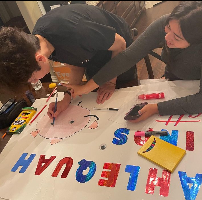 Two students leaders from Tahlequah High School lean over a poster as they decorate a poster that says "Tahlequah Minds Matter" and advertises their "Gratitude Week"