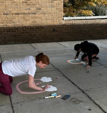 Eagles Minds Matter students make chalk drawings outside of Robert Frost Middle School.